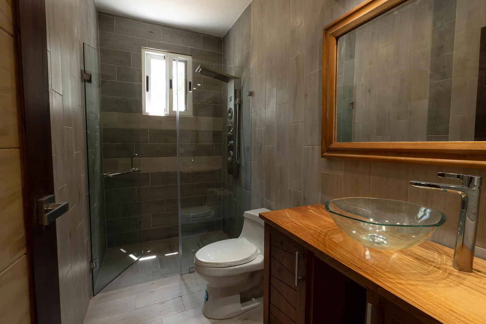 Baño terminado con revestimientos, mampara y mobiliario en una vivienda de Coronado